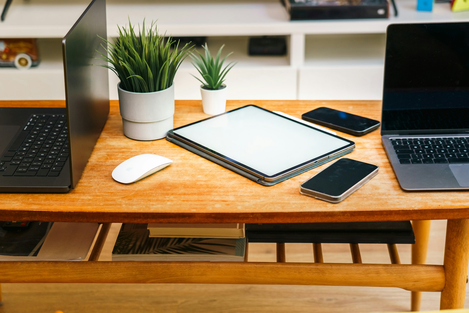 Devices like laptops, tablets, and phones are on a desk.